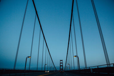 Low angle view of suspension bridge against clear blue sky