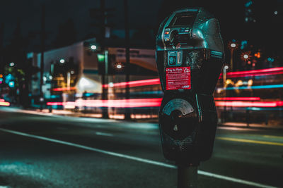 Close-up of telephone on street in city at night