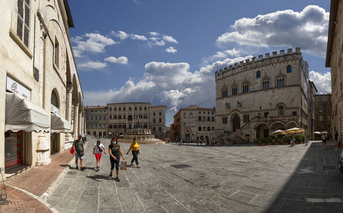 People walking on historic building in city against sky