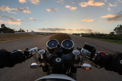 Motorcycle on road against sky during sunset