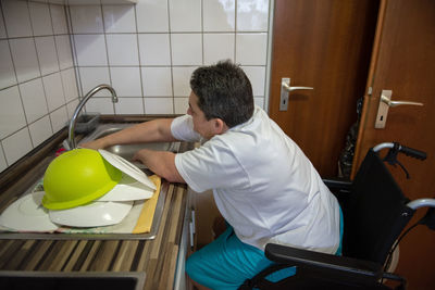 Rear view of boy sitting in bathroom