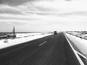 Road amidst snow covered land against sky