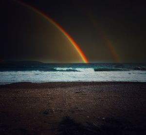 Scenic view of rainbow over sea against sky