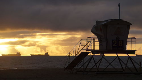 Lifeguard tower on the beach and barges in the pacific ocean at sunset 