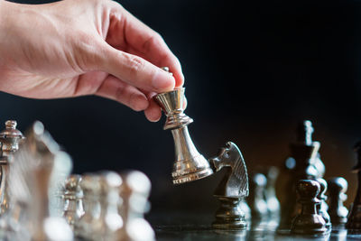 Cropped hand playing chess against black background