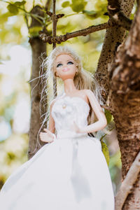 Portrait of woman with arms raised standing against tree