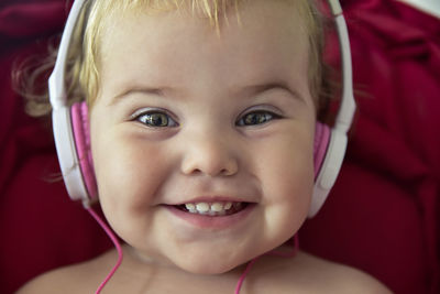 Close-up portrait of smiling girl listening music at home