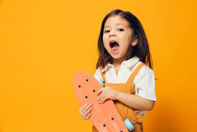 Portrait of young woman standing against yellow background