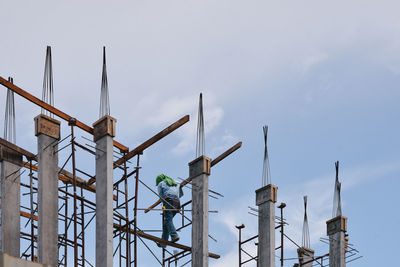 Low angle view of mason working at construction site against sky