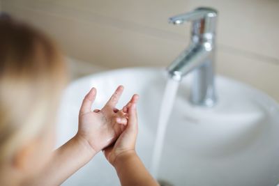 Close-up of girl washing hands by bathroom sink