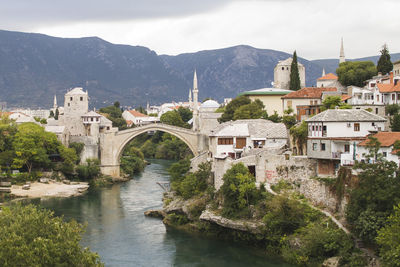 Arch bridge over river in town against sky