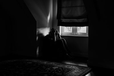 Depressed man with head in hand sitting on floor at home