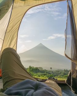 Low section of tent view of volcano against sky