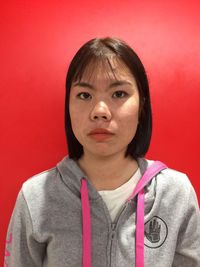 Portrait of woman standing against red wall