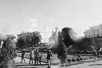 People at fountain in city against sky