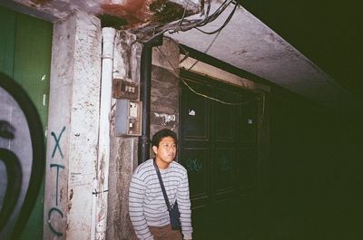 Portrait of young man looking away against building wall