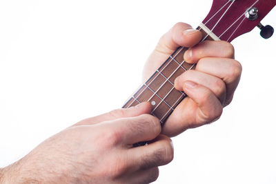 Midsection of man playing guitar against white background