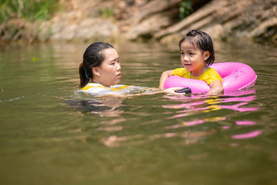 Mother by girl with inflatable raft in lake