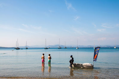 Rear view of people on beach against sky