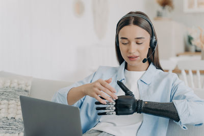 Portrait of young woman using mobile phone while sitting at home