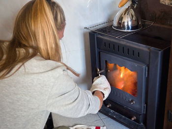 Midsection of woman preparing food at microwave oven