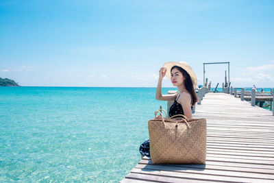 Woman by sea against blue sky