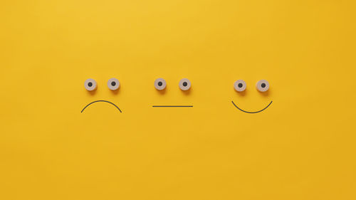 Close-up of smiley face against yellow background