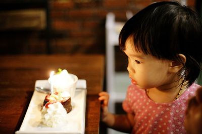 High angle view of baby girl looking at cupcake on table