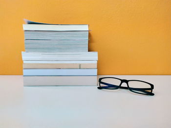 Close-up of books on table against orange wall