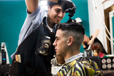 Barber cutting hair of man at salon