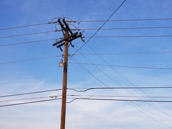 Low angle view of electricity pylon against blue sky