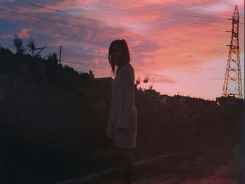 Silhouette of man standing on landscape at sunset