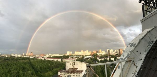 Rainbow over buildings in city against sky