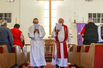 Priest reading books with people in church