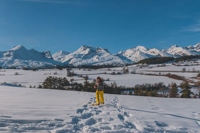 A full-body shot of a young caucasian woman running towards the camera in the french alps mountains