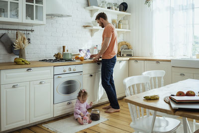 Businessman working on laptop while daughter playing at kitchen