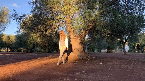 Woman standing by road against trees