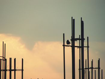 Low angle view of silhouette wooden post against sky during sunset