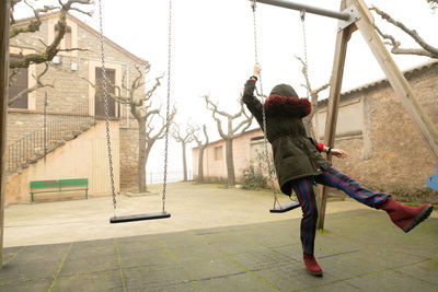 Young girl sheltered in an abandoned swing set with hood, unrecognisable.