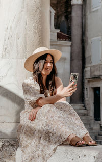 Full length of young woman using mobile phone outdoors