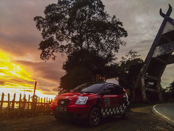 Car on street against sky at sunset