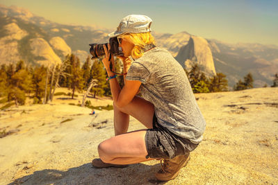 Woman photographing against mountain range 