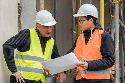 Engineers discussing while standing at construction site