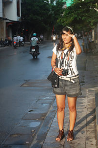 Full length of woman standing on road in city