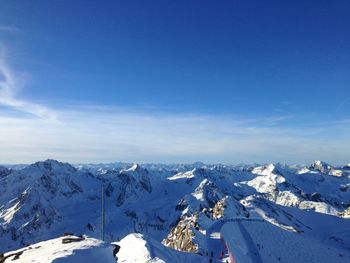 Aerial view of snowcapped mountains against blue sky