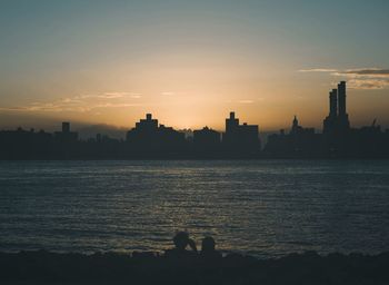 Silhouette buildings against sky at sunset