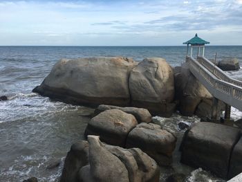 Rocks on shore by sea against sky