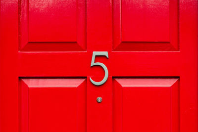 House number 5 on a red wooden front door in london 