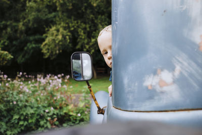 Boy looking through vintage car window