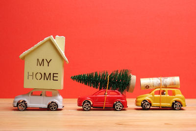 Toy cars with model house against red background